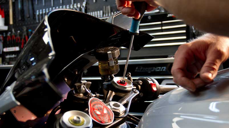 Motorradmechaniker Sven Kurtenbach bei der Einstellung des Fahrwerks am Motorrad