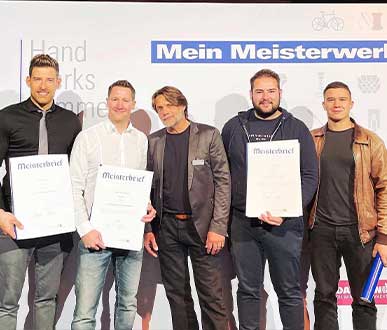 Foto mit mehreren Personen, welche ihre Meisterbreife vor sich halten, Netzwerk aus Motorradmeister-Werkstatt-Betreibern